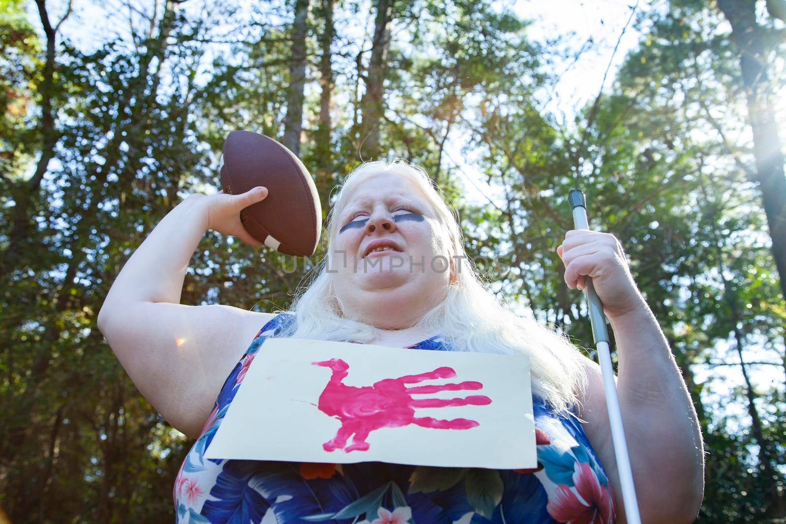 Albino woman wearing a paper hand-turkey napkin, throwing a football