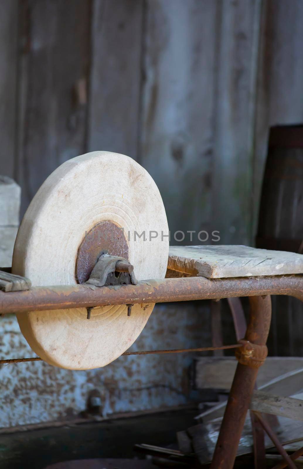 Old stone grinding machine on a wooden platform