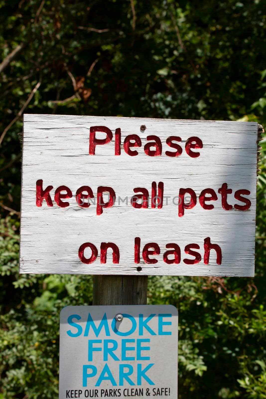 White sign telling patrons to "Please keep all pets on leash" and that the park is a"Smoke Free Park"