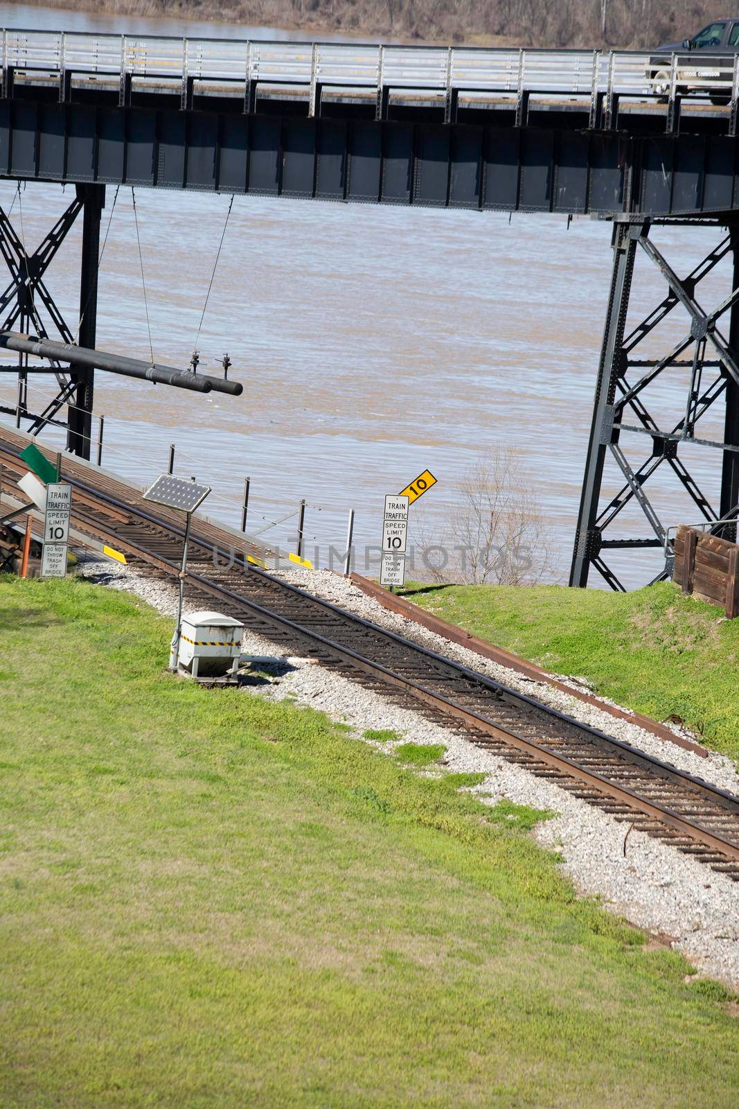 Train tracks crossing a river, signs that denote "Train traffic," "Speed limit 10" miles per hour, and "Do not throw trash off bridge"