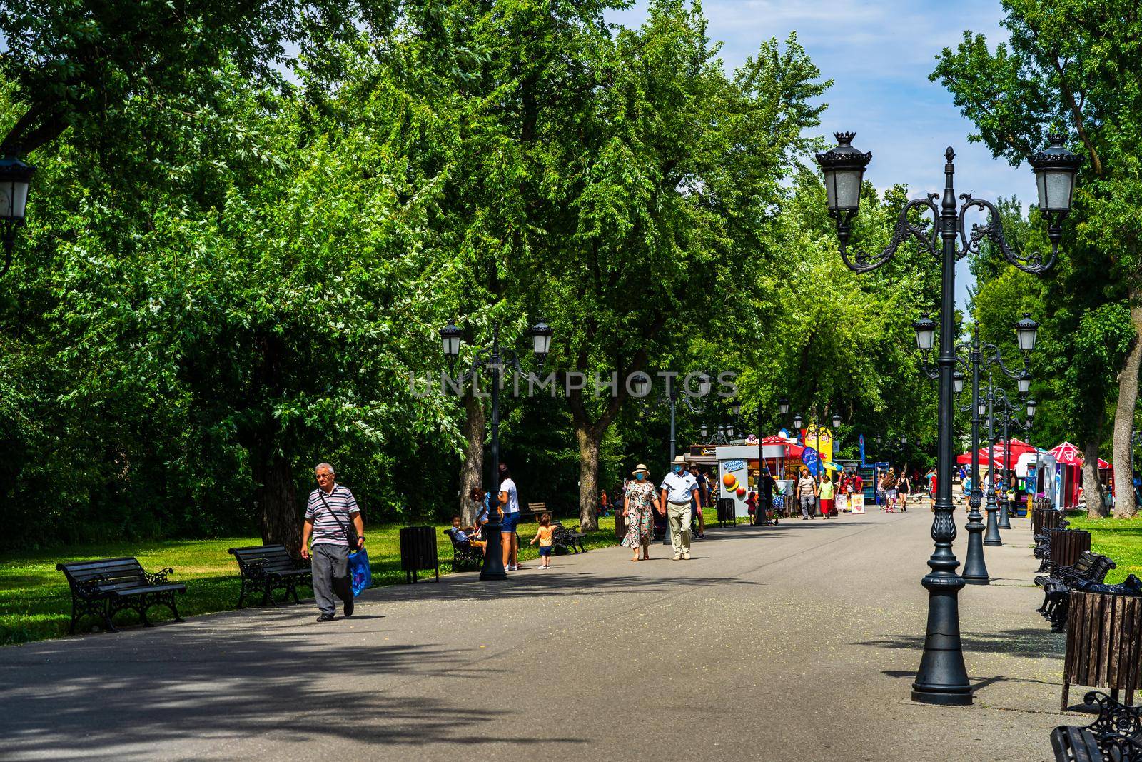 Old couple wearing surgical mask holding hands, people walking, relaxing and have fun on the alleys of park and gardens of the domain from Mogosoaia in Bucharest, Romania, 2020. by vladispas