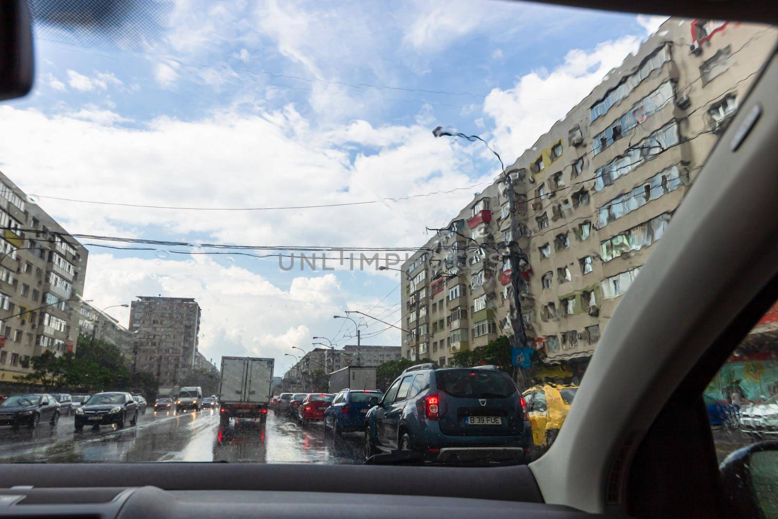 Traffic in cloudy rainy day with road view through car front window in Bucharest, Romania, 2020 by vladispas