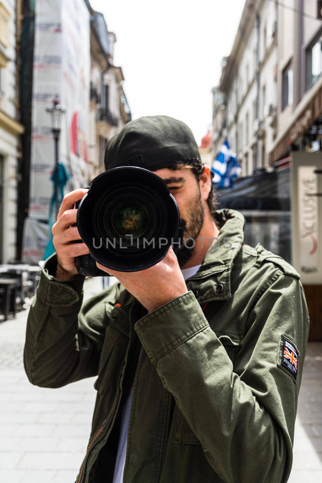 Street photographer taking photos with DSLR camera and telephoto lens in Old Town of Bucharest, Romania, 2020