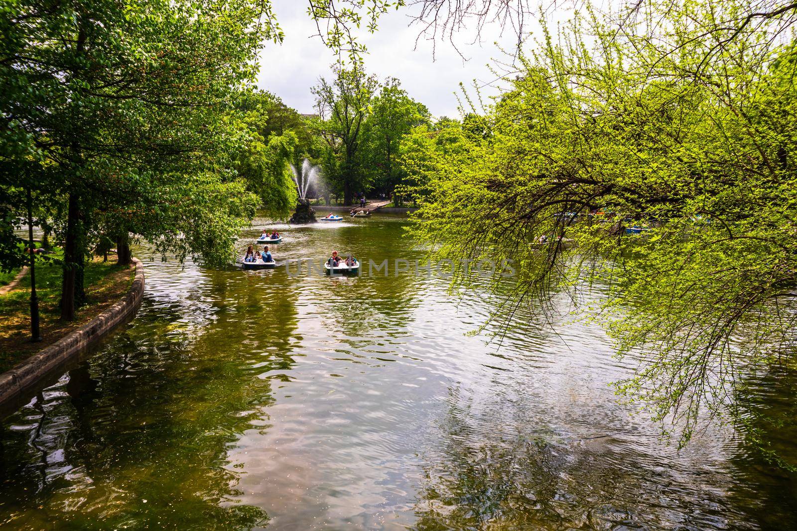 People on pedal boat on lake in Cismigiu Park, Bucharest, Romania, 2020. People walking, having fun, enjoying outdoor in park after quarantine or restrictions of coronavirus. by vladispas