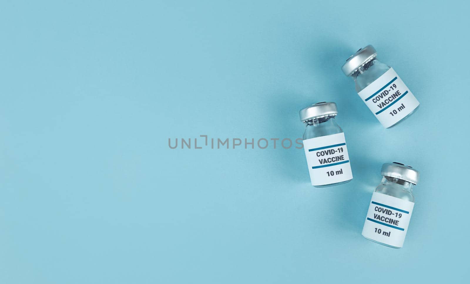 Medicine bottles with covid 19 vaccine on blue background with copy space.