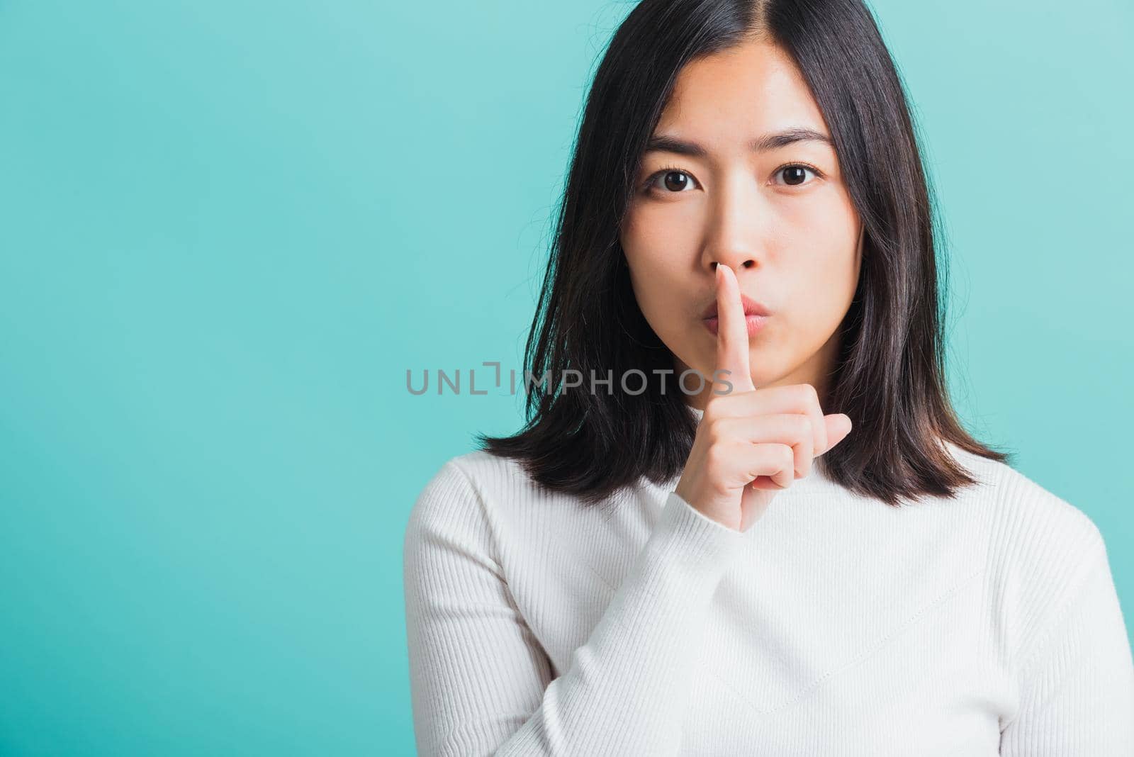 woman holding index finger on her mouth lips by Sorapop