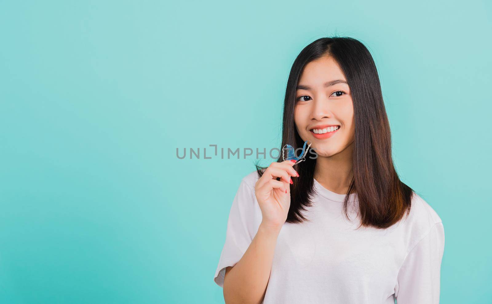 Portrait young Asian beautiful woman smiling holding silicone orthodontic retainers for teeth, Teeth retaining tools after removable braces, Orthodontics dental healthy care concept 