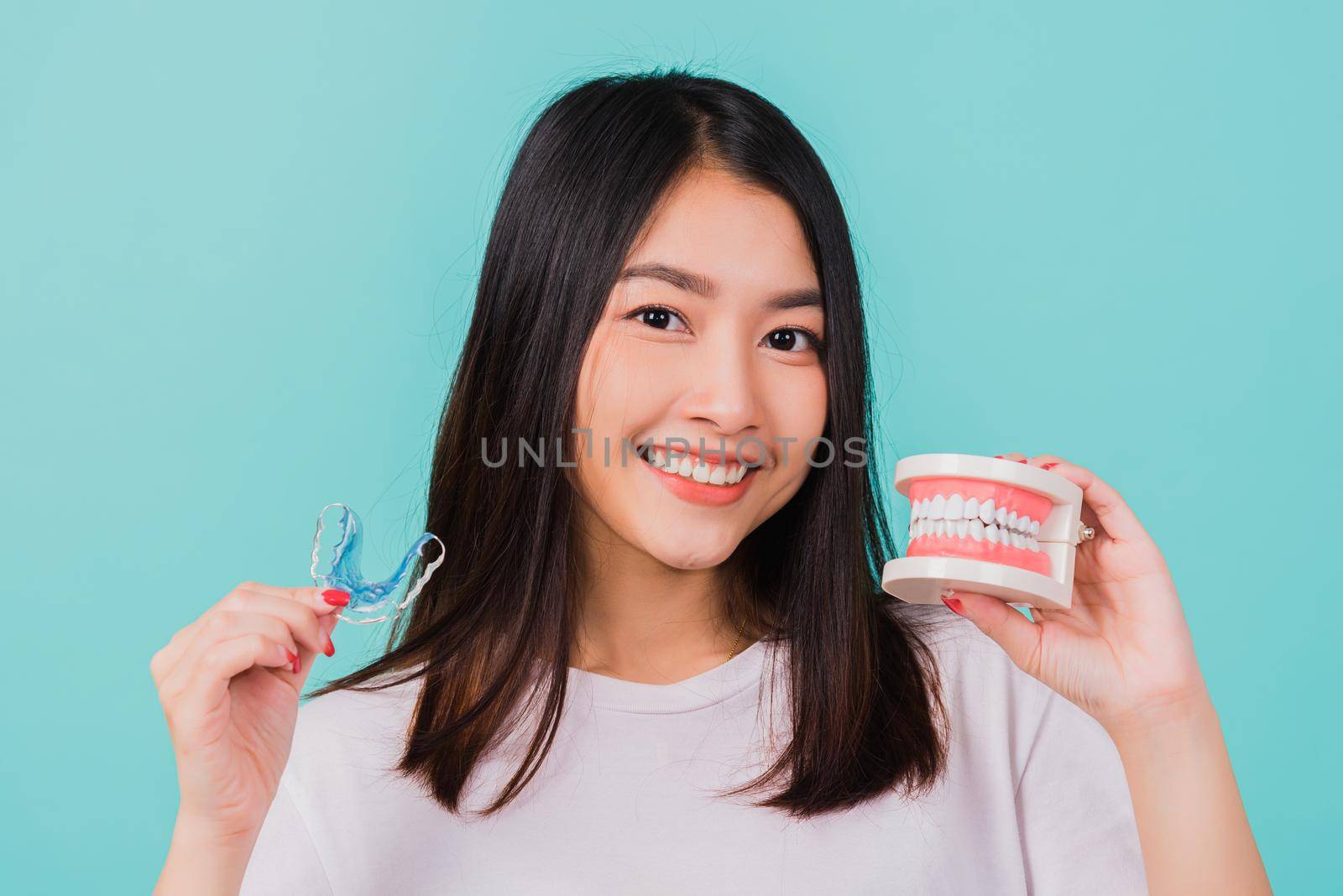 Portrait young Asian beautiful woman smiling holding silicone orthodontic retainers for teeth retaining tools after removable braces, Female hold model teeth before, Orthodontics dental healthy care