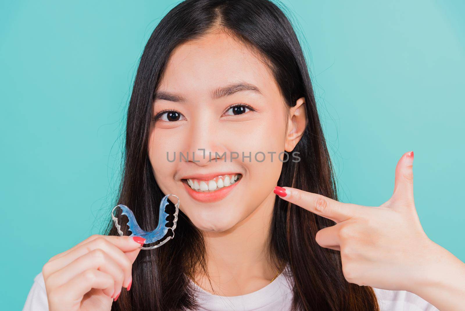 Female hold teeth retaining tools after removable braces, Portrait young Asian beautiful woman smiling pointing with finger silicone orthodontic retainers for teeth, Orthodontics dental care concept