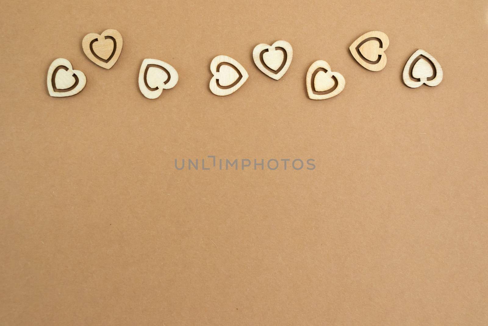 Wooden hearts on a pastel craft paper background. Abstract background with wood cut shapes. Sainte Valentine, mother's day, birthday greeting cards, invitations. Copy space.