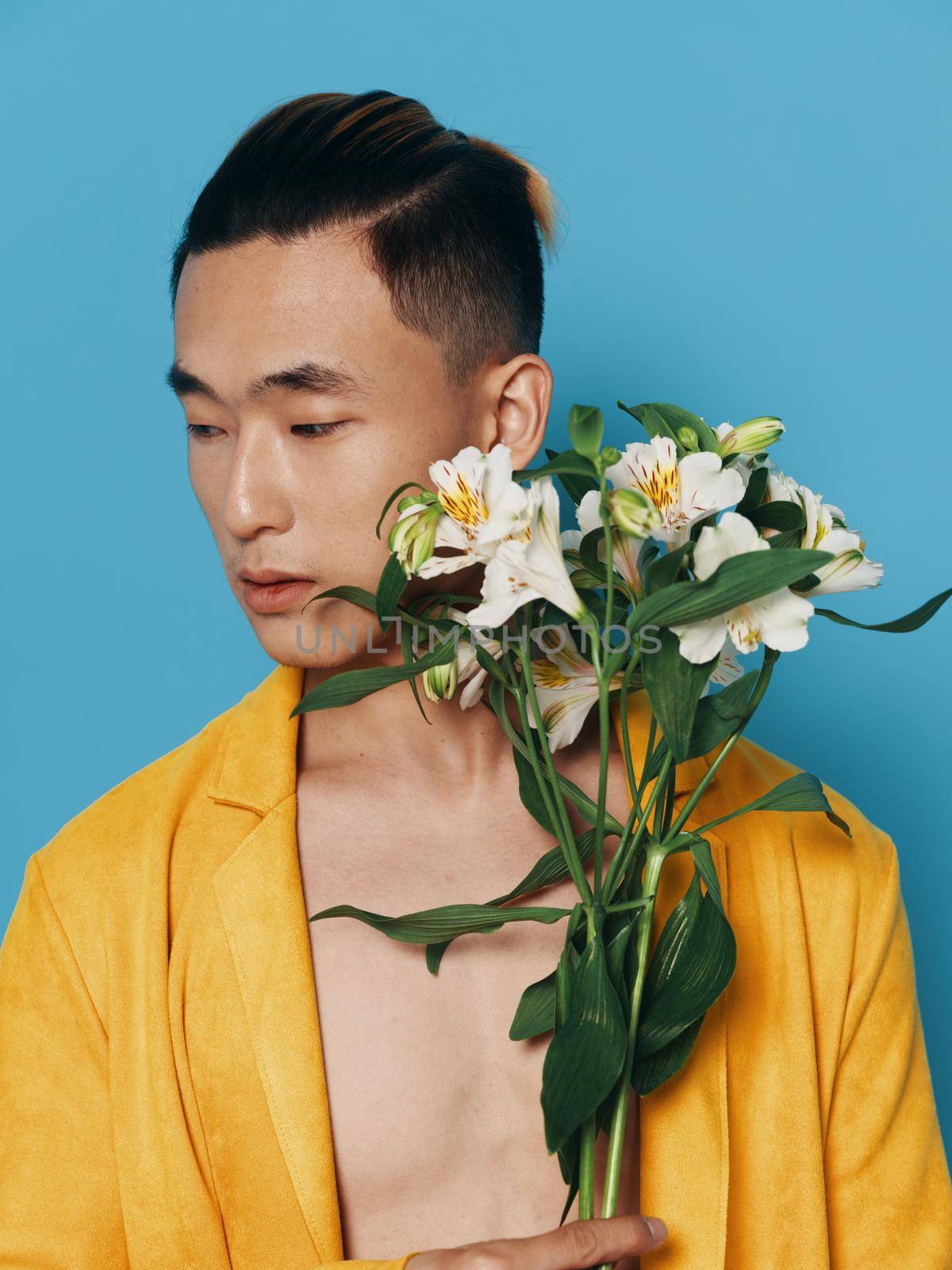 romantic man with a bouquet of flowers on a blue background and a yellow coat, Asian appearance by SHOTPRIME