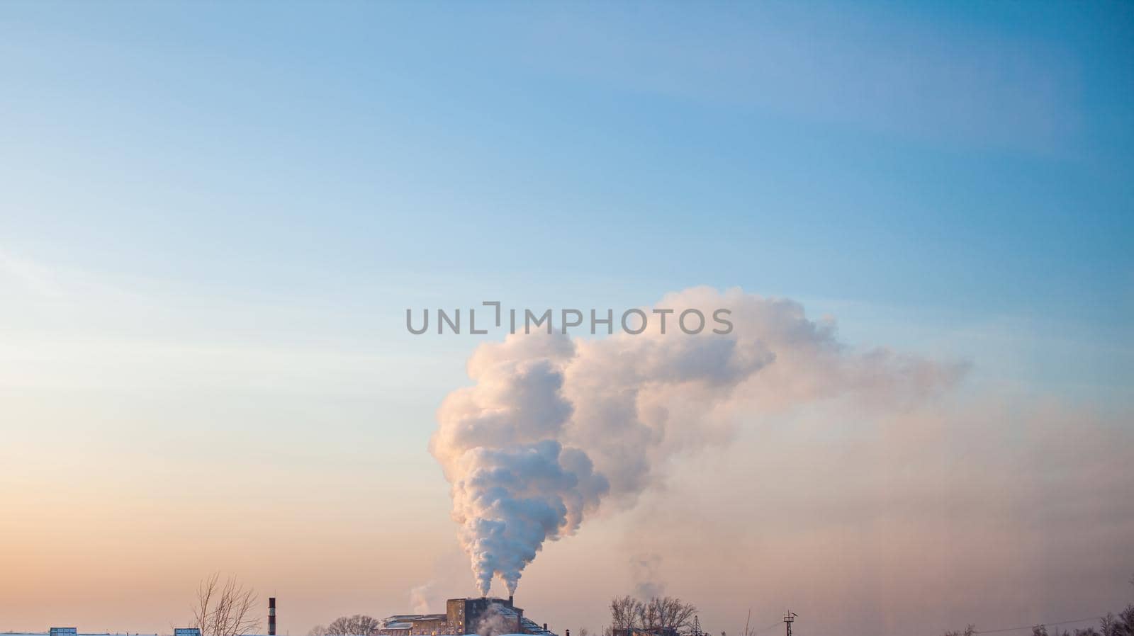 White thick smoke from the boiler room chimney. Smoke against the blue sky. Air pollution. Heating of the city. Industrial zone.