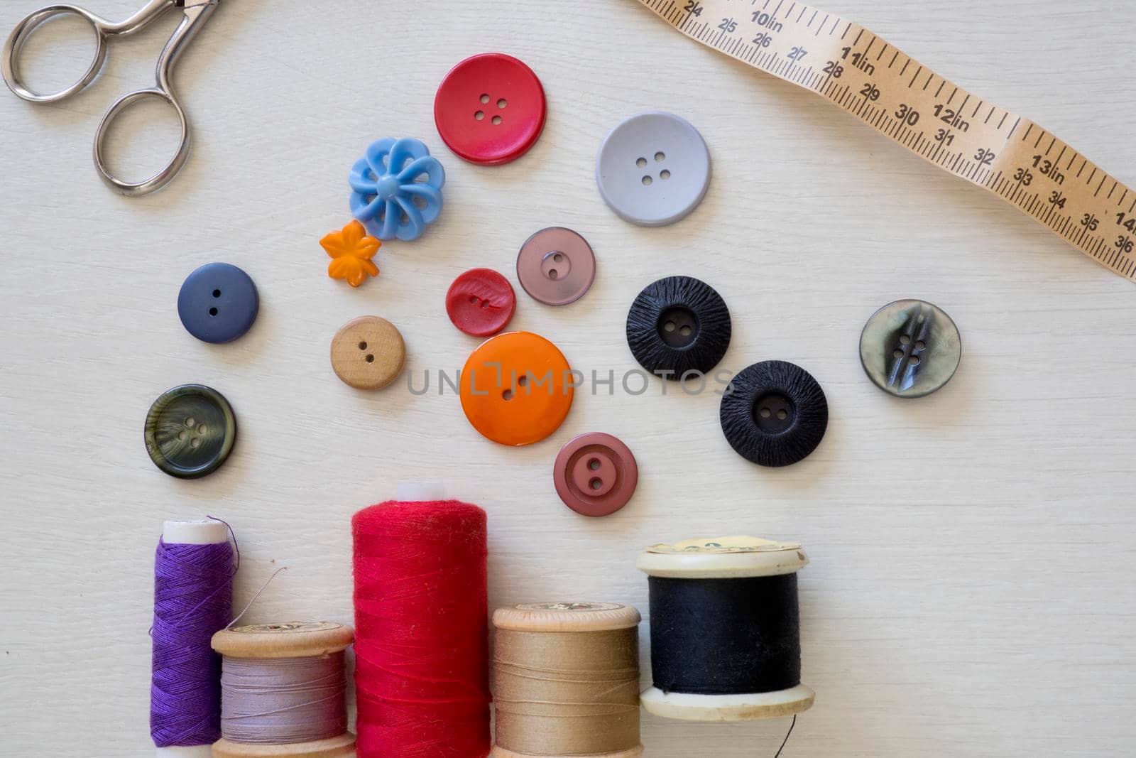 Brightly colored buttons and sewing cotton, flat lay by fivepointsix