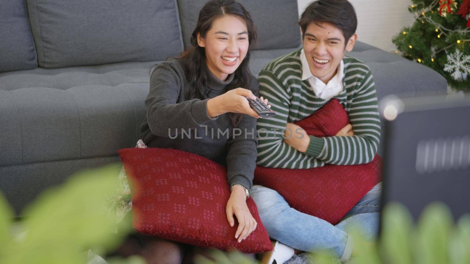 Happy Asian beautiful young family couple husband and wife enjoying in living room winter at home watching TV television entertainment or movie together