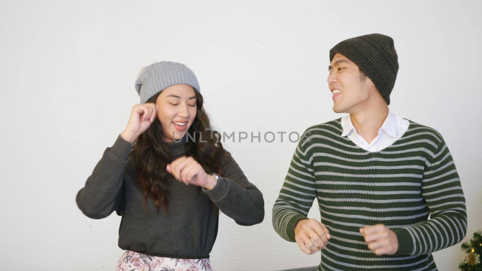 husband and wife smile dancing laughing around christmas tree at home living room by Sorapop