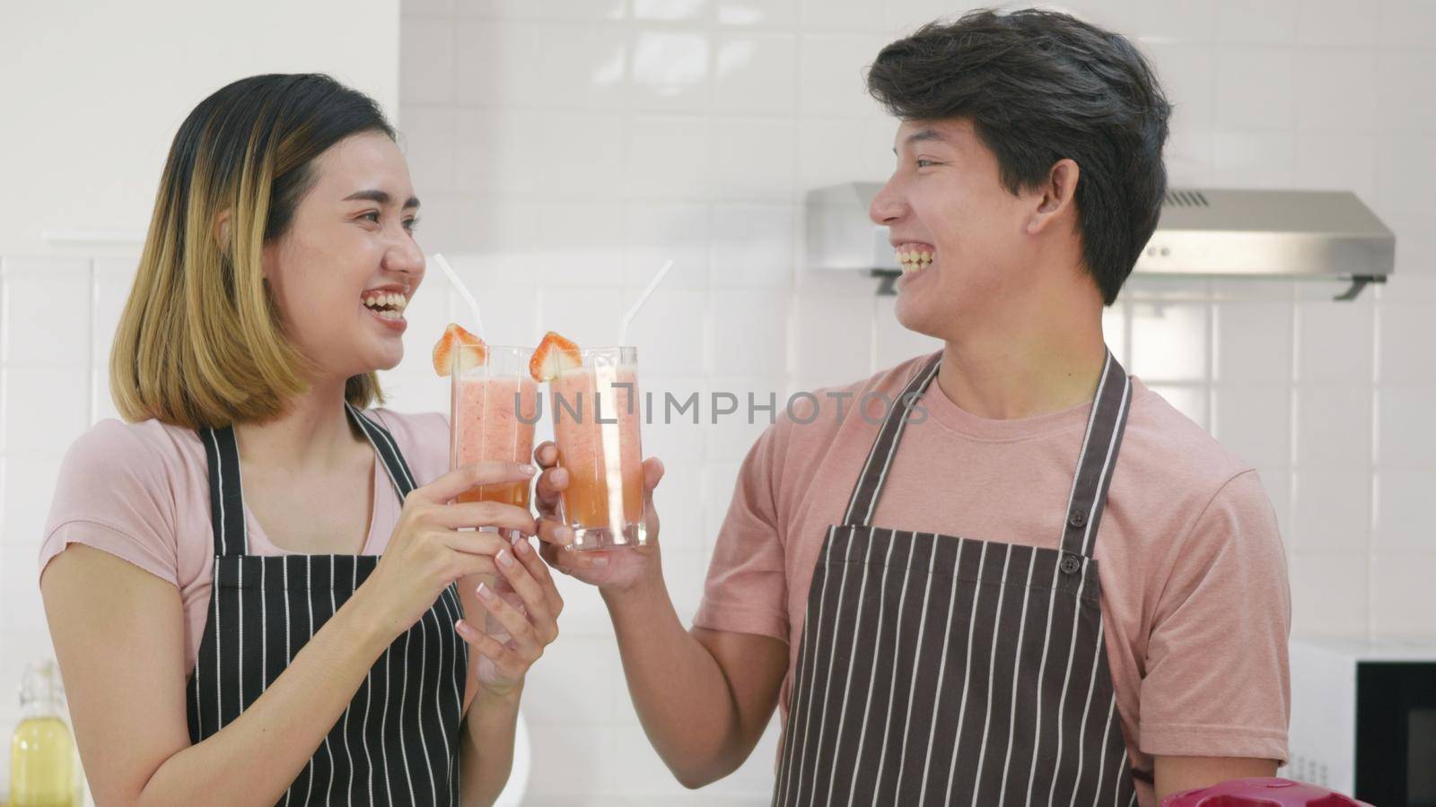 family couple husband and wife enjoying drinking fresh apple smoothie juice in kitchen by Sorapop