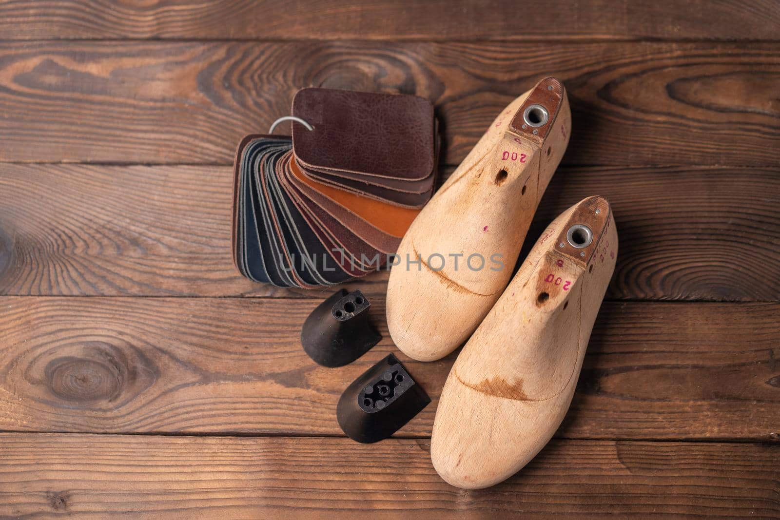 Leather samples for shoes and wooden shoe last on blue wooden table. Designer furniture clothes. Shoe maker workspace.