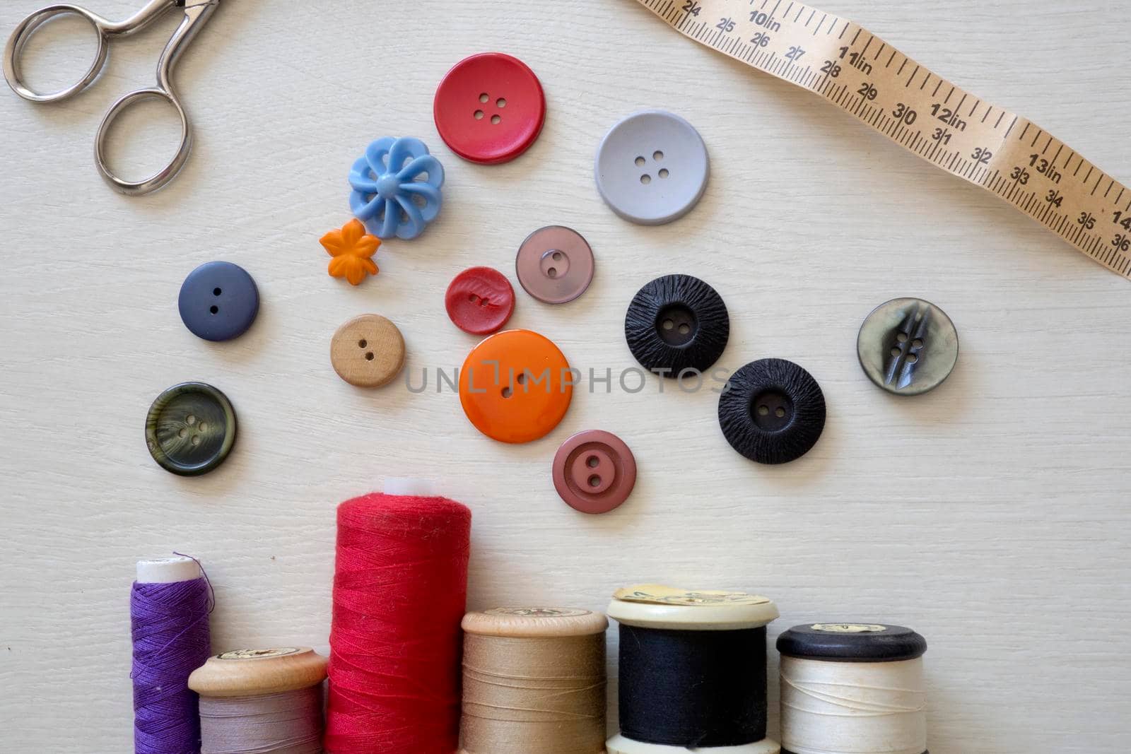 Brightly colored buttons and sewing cotton, flat lay by fivepointsix