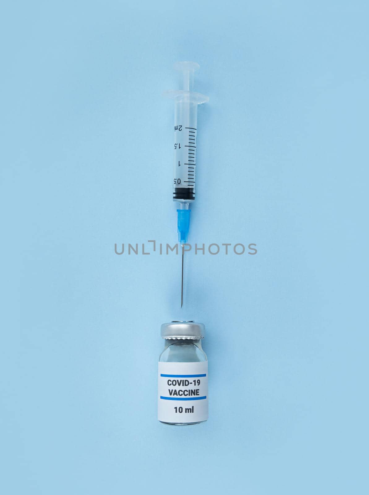 Single use syringe and medical bottle with coronavirus vaccine on a blue background.
