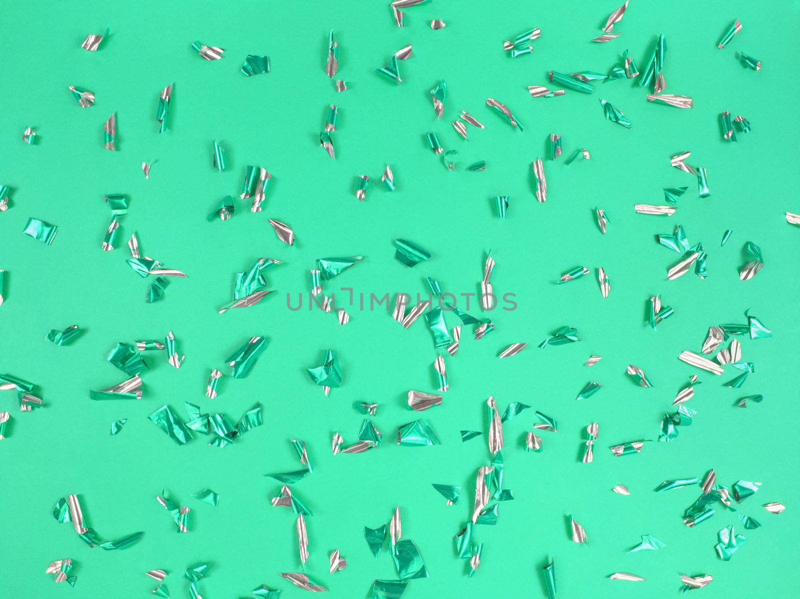 Confetti foil pieces on a green background. Abstract festive backdrop.