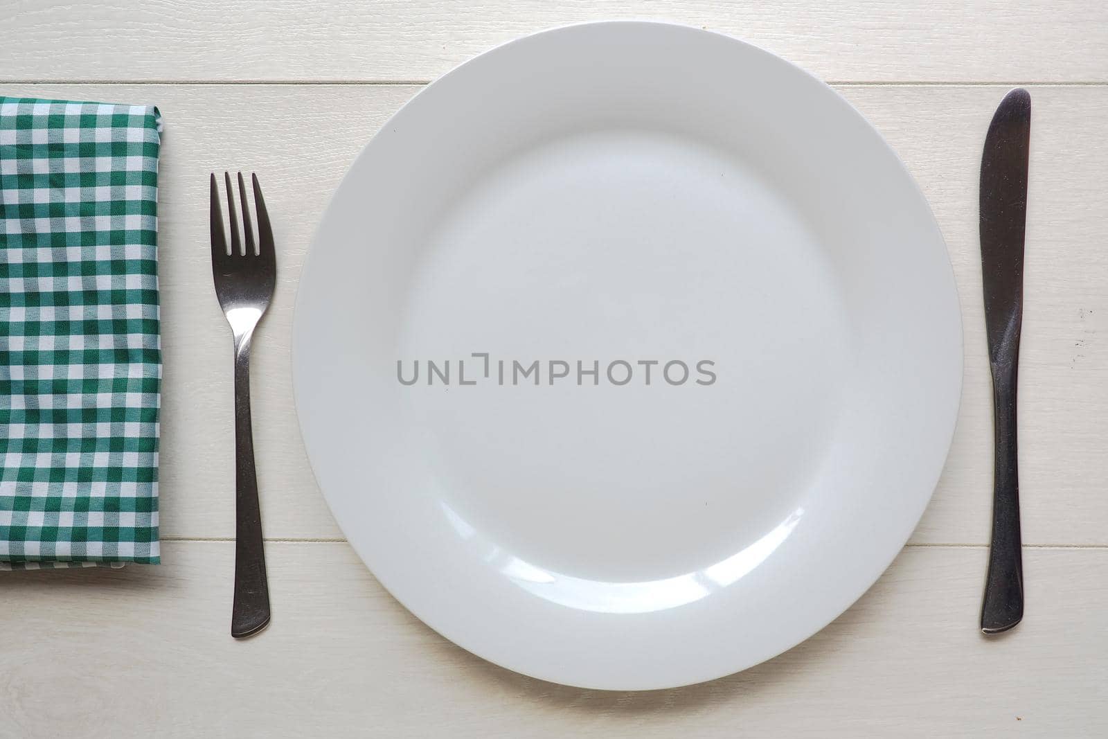 White plate and knife and fork on white wooden background by fivepointsix