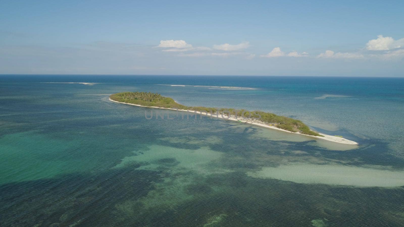 Tropical island with white sandy beach, palm trees. Aerial view of Tanduyong island with colorful reef. Seascape, ocean and beautiful beach. Philippines, Anda, Pangasinan. Travel concept.