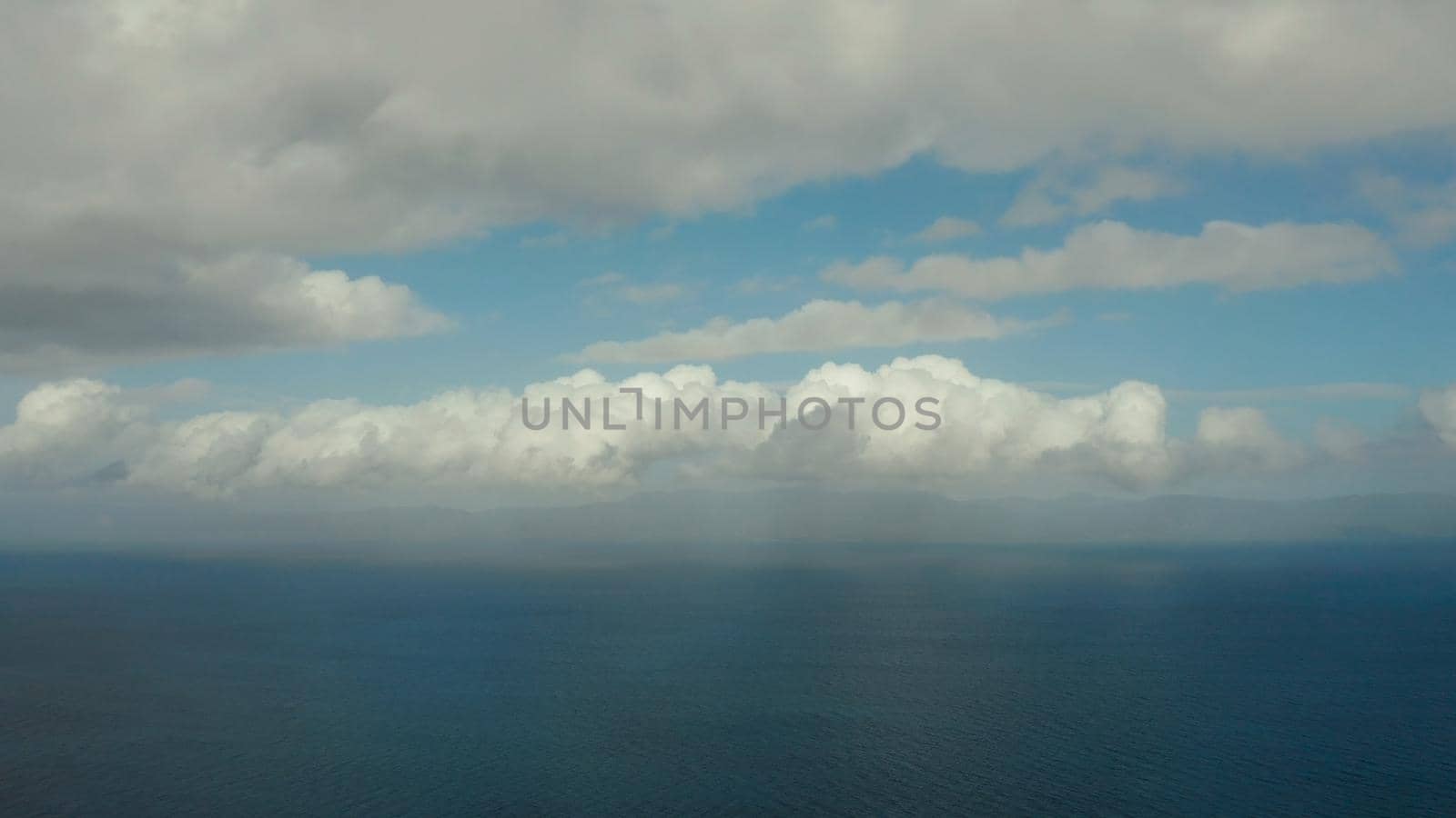 Seascape in cloudy weather, aerial view. Water cloud horizon background. Blue sea water with small waves against sky.