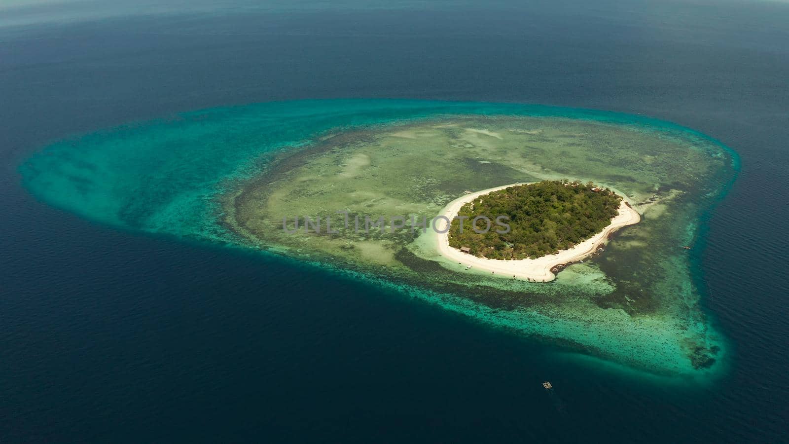 Tropical island and sandy beach surrounded by atoll coral reef and blue sea, aerial view. Small island with sandy beach. Summer and travel vacation concept, Mantigue Philippines Mindanao