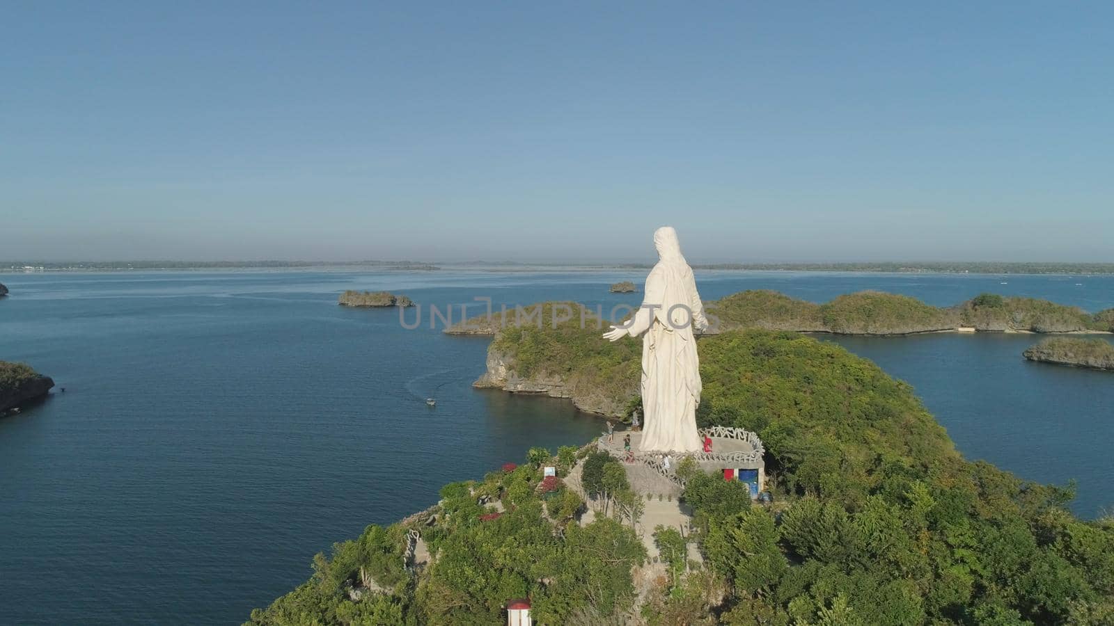 Statue of Jesus Christ on Pilgrimage island in Hundred Islands National Park, Pangasinan, Philippines. Aerial view of group of small islands with beaches and lagoons, famous tourist attraction, Alaminos.