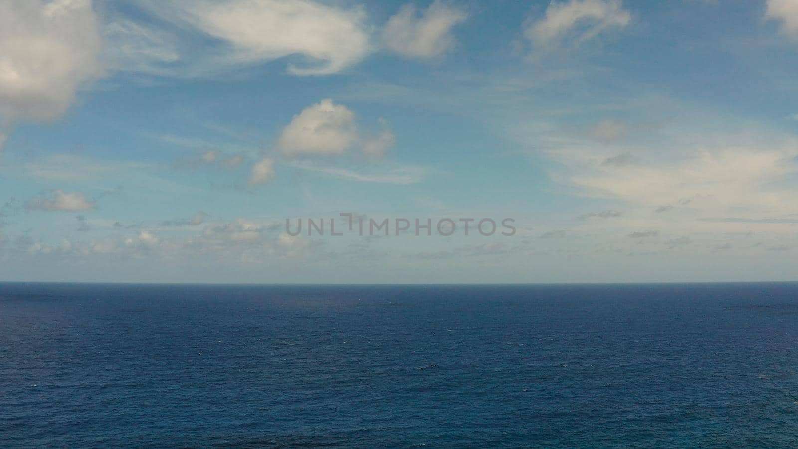 Blue ocean with waves and sky with clouds, seascape top view. Water cloud horizon background. Blue sea water with waves against sky.