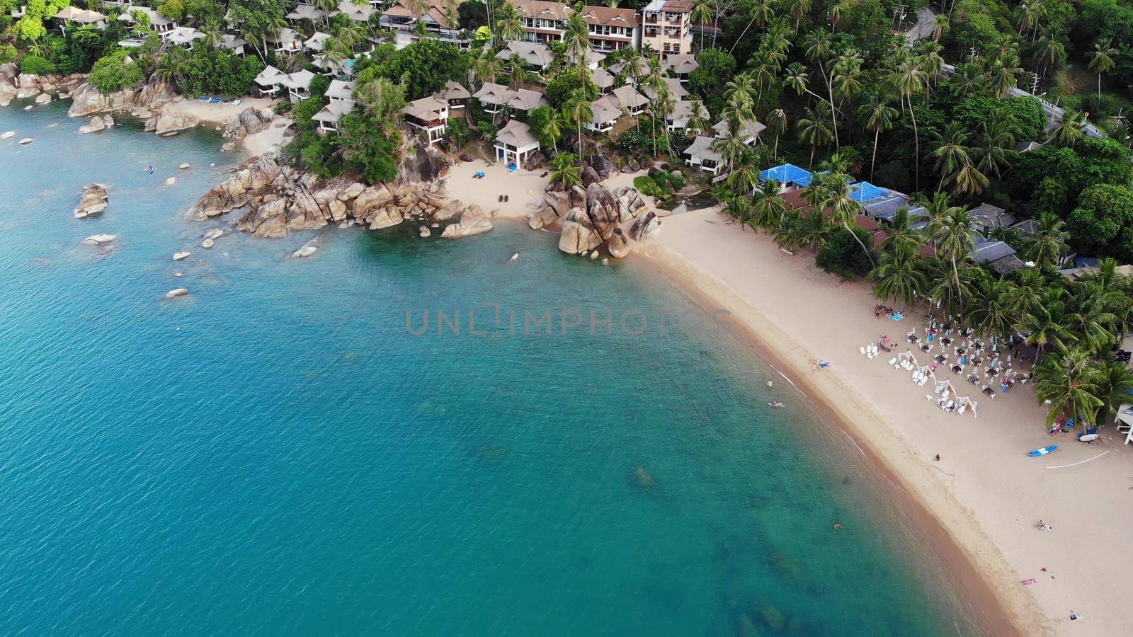 Villas on green mountain ridge. Majestic drone view of luxury villas located on green mountain range on tropical paradise island near the tiny beach. Stony shore and green jungle, volcanic Koh Samui