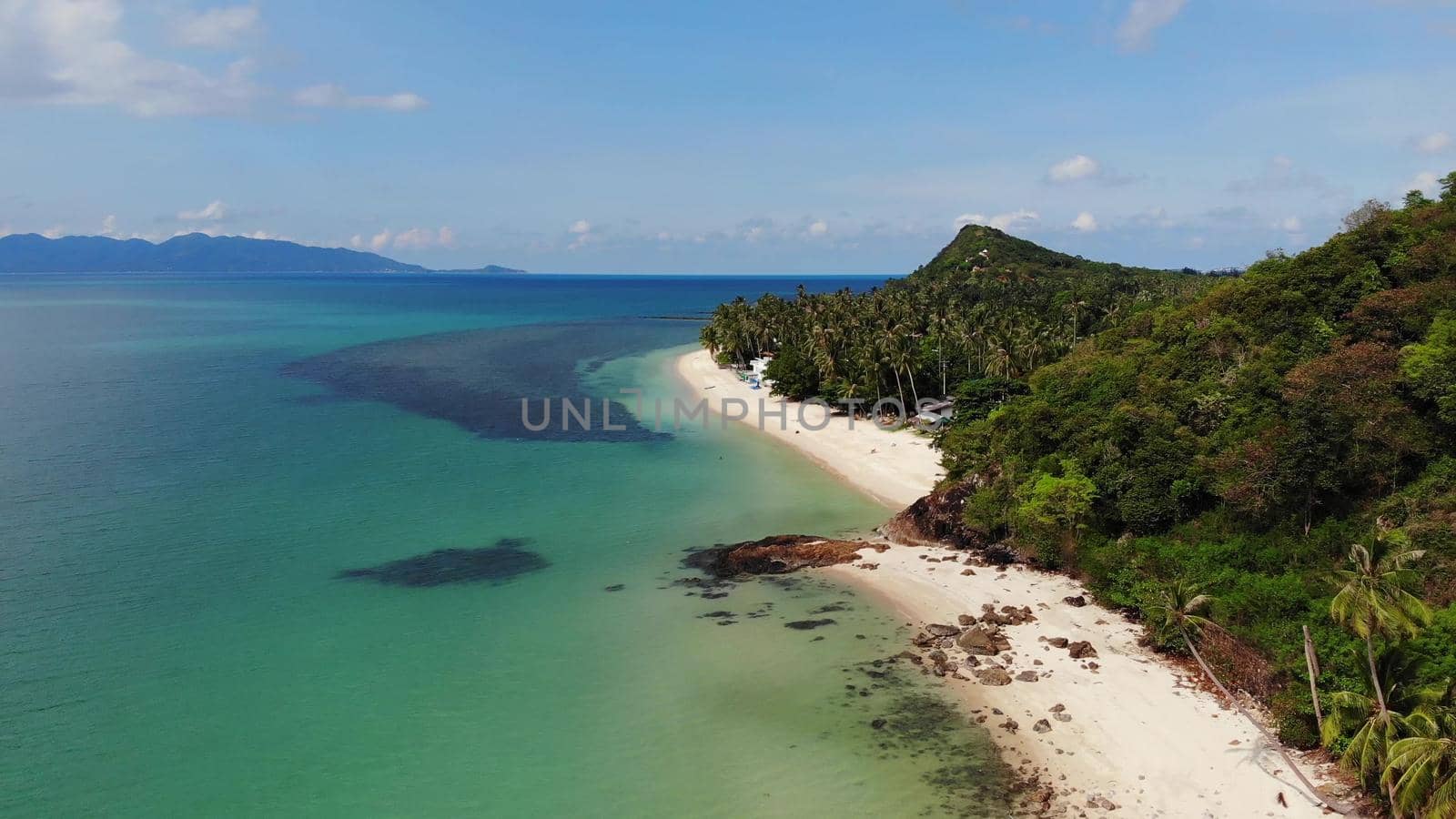 Green jungle and stony beach near sea. Tropical rainforest and rocks near calm blue sea on white sandy shore of Koh Samui paradise island, Thailand. Dream beach drone view. Relax and holiday concept