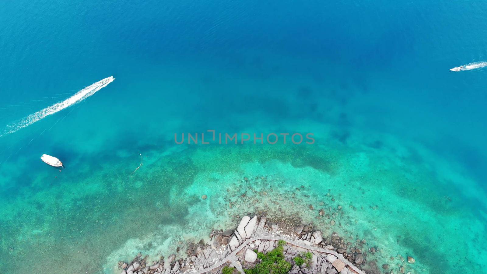 Calm colorful azure turquoise sea near tiny tropical volcanic island Koh Tao, unique small paradise Nang Yuan. Drone view of peaceful water near stony shore and green jungle on sunny day in Thailand