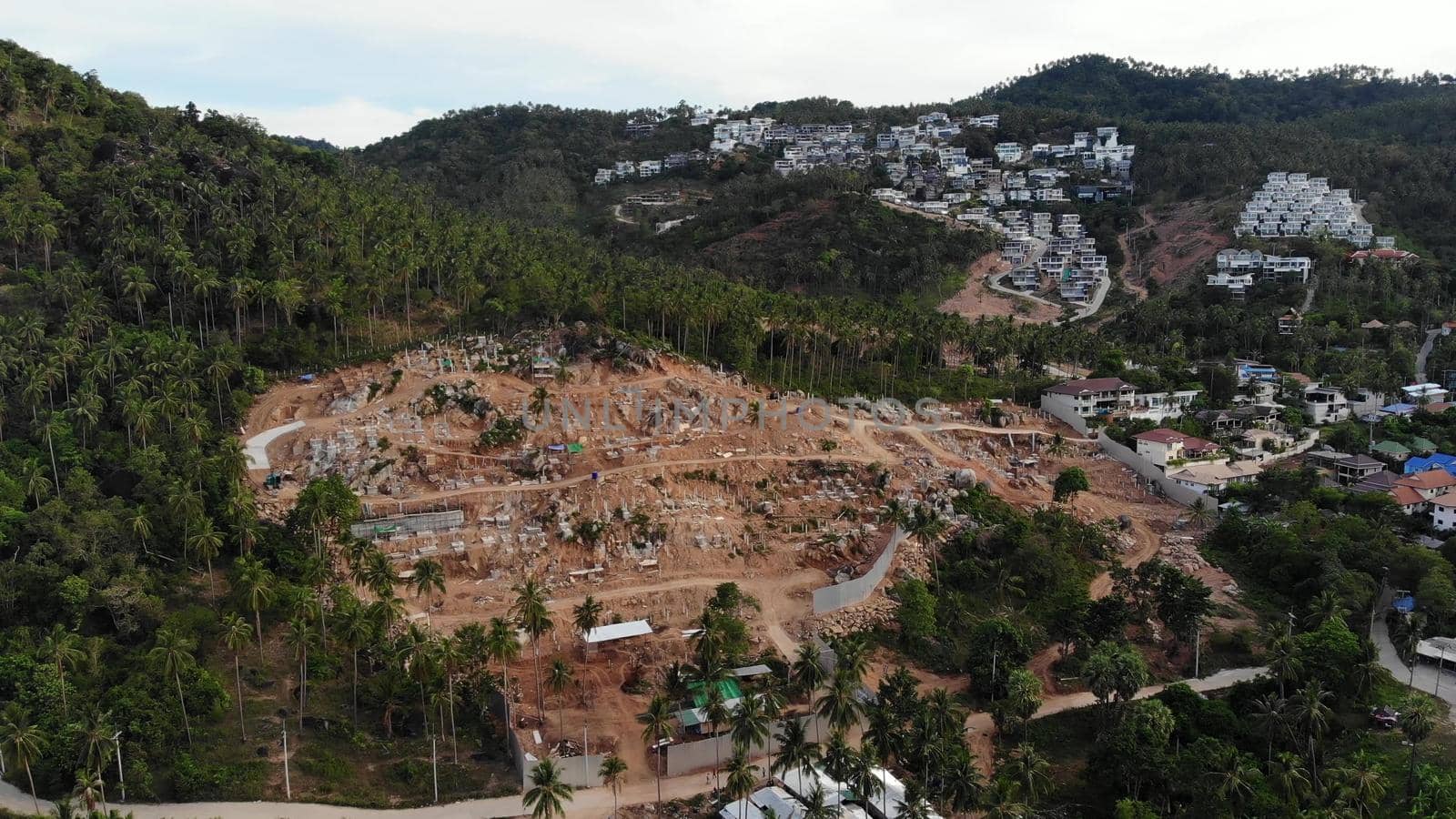 Tropical terrain covered with endangered forests and luxury villas. Drone view of large tropics with ecosystem disturbance due to buildings and deforestation. Koh Samui. Coconut palm plantations