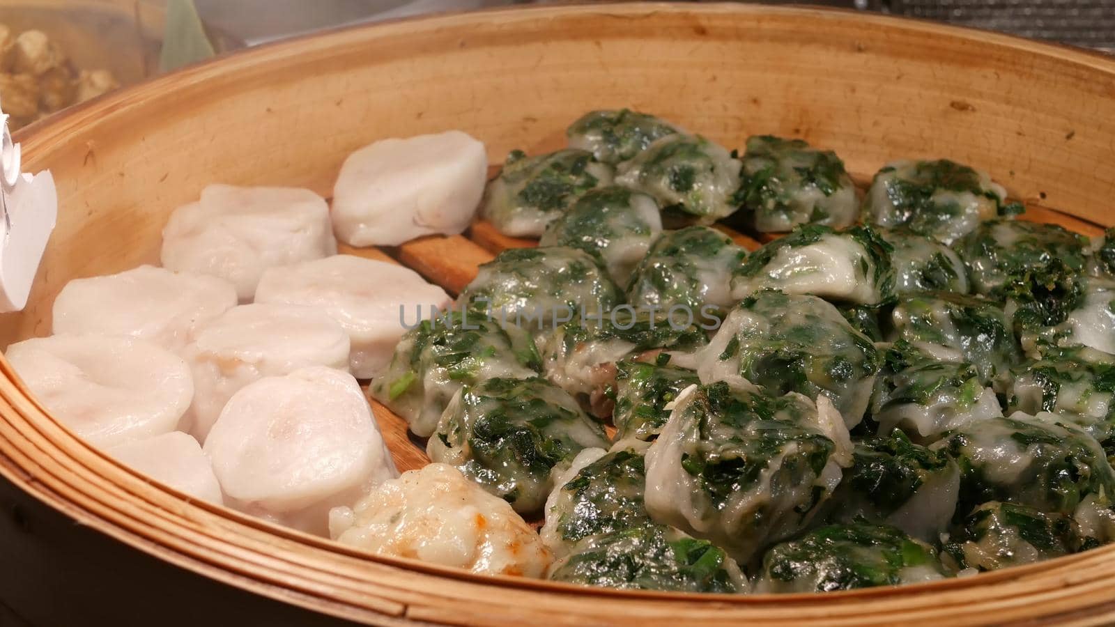 Bowl with hot Asian dumplings. Wooden bowl with delicious traditional Thai dumplings placed on stall in street diner.