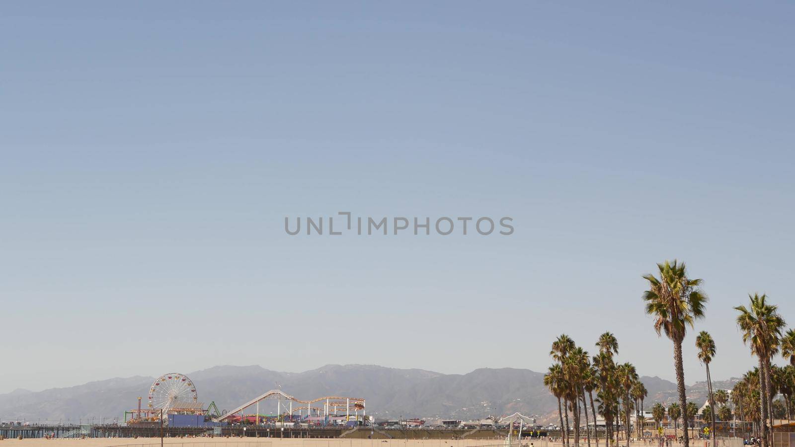California beach aesthetic, classic ferris wheel, amusement park on pier, Santa Monica pacific ocean resort. Summertime iconic view, palm trees and sky, symbol of Los Angeles with copy space, CA USA.
