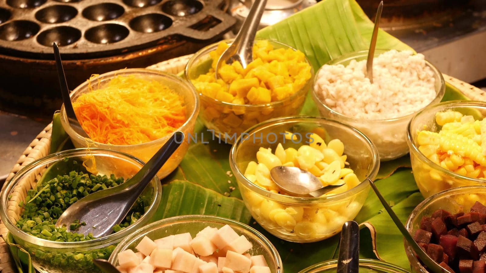 Exotic Oriental Asian sweet delicious desserts, unusual colorful traditional dishes on the counters of a bazar with street food. Evening food court in bangkok, the capital of cooking. Night market.