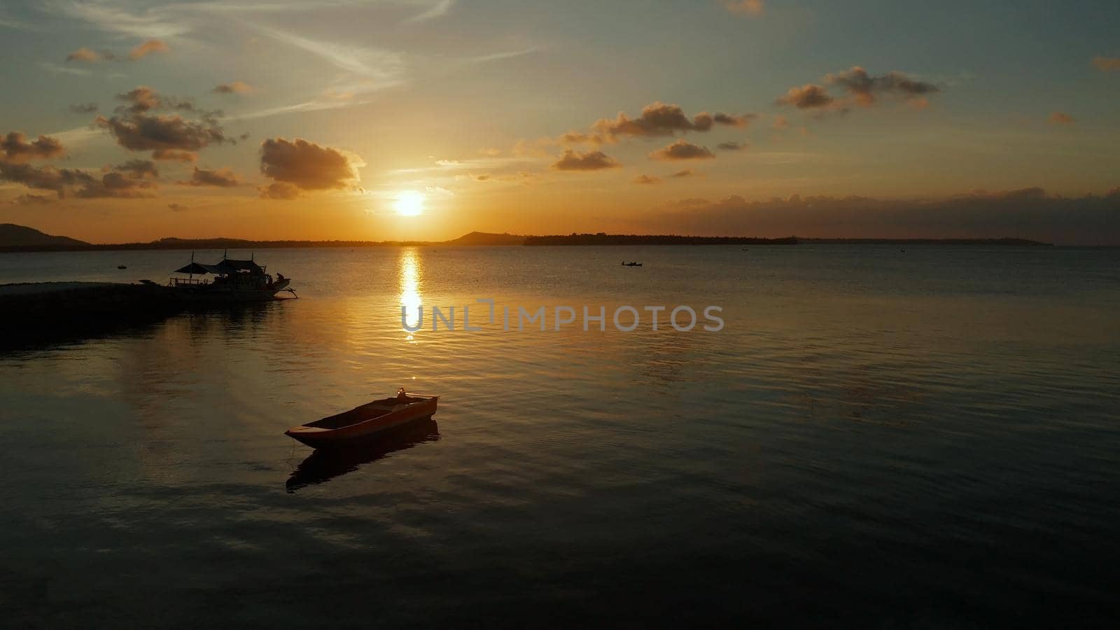 Colorful bright clouds during sunset over the sea, aerial view. Reflected sun on a water surface. Sunset over ocean. Balabac, Palawan, Philippines