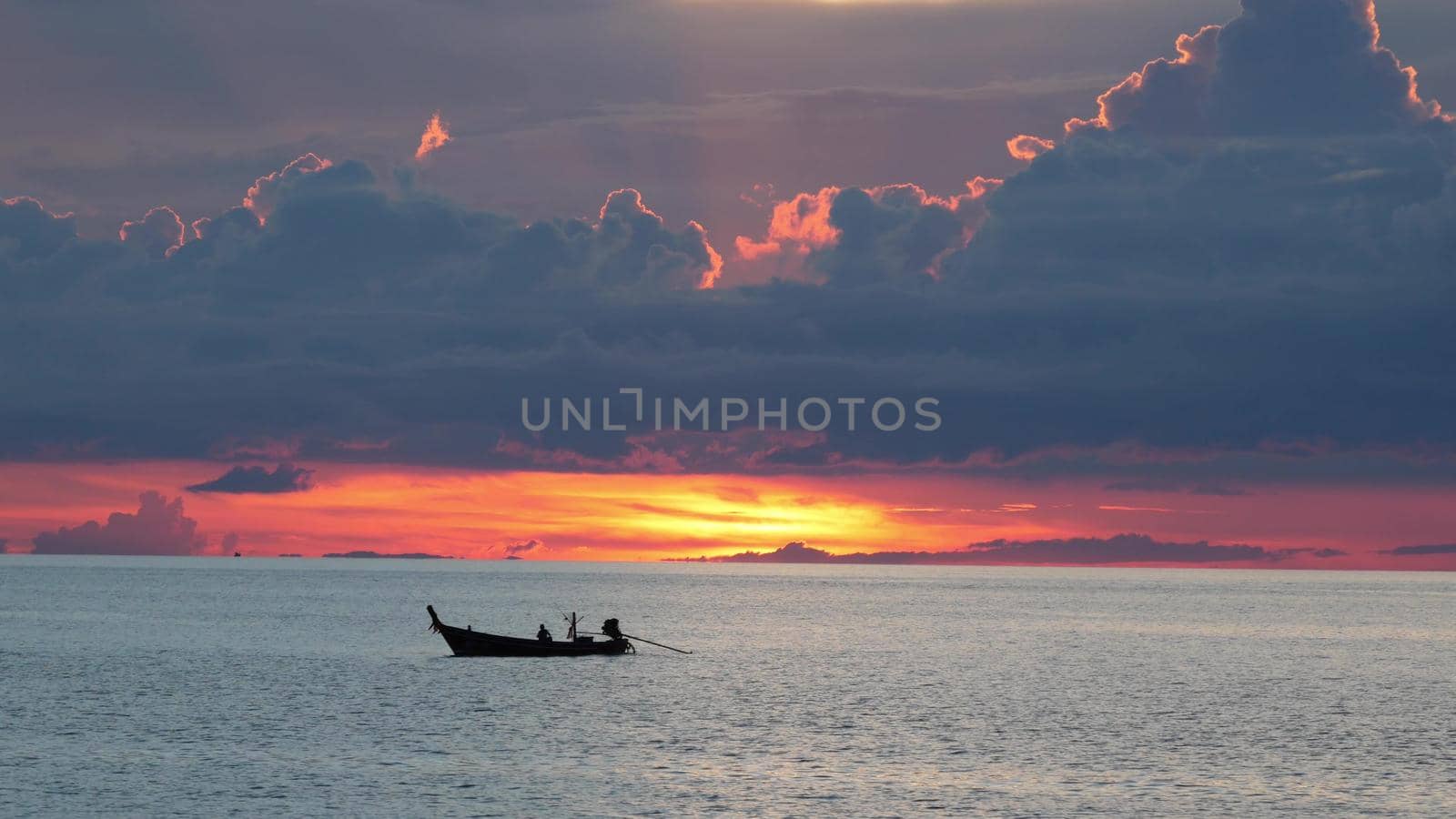 Boat in sea during sunset. Silhouette of small rowing boat floating on rippling water of calm sea during sundown in cloudy evening. Paradise tropical romantic natural background