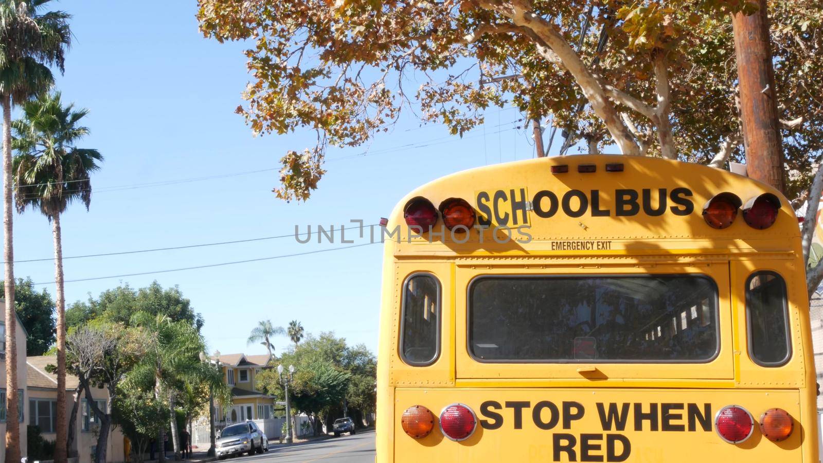 Yellow iconic school bus in Los Angeles, California USA. Classic truck for students back view. Vehicle stoplights for safety of children transportation. Public passenger transport for kids in suburb.