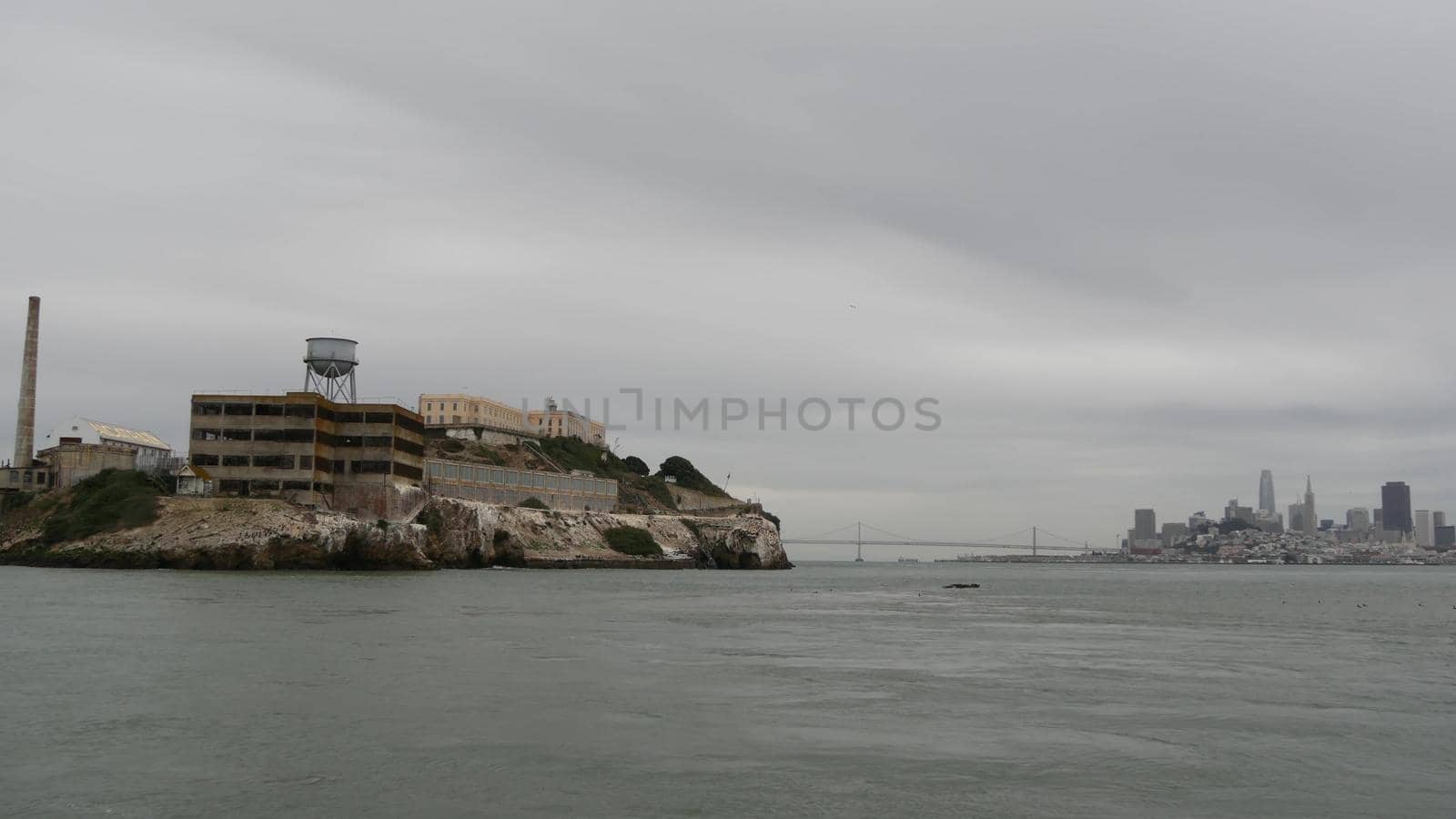 Alcatraz island in San Francisco Bay, California USA. Federal prison for gangsters on rock, foggy weather. Historic jail, cliff in misty cloudy harbor. Gaol for punishment and imprisonment for crime.