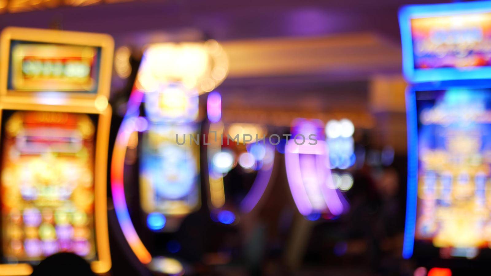 Defocused slot machines glow in casino on fabulous Las Vegas Strip, USA. Blurred gambling jackpot slots in hotel near Fremont street. Illuminated neon fruit machine for risk money playing and betting.