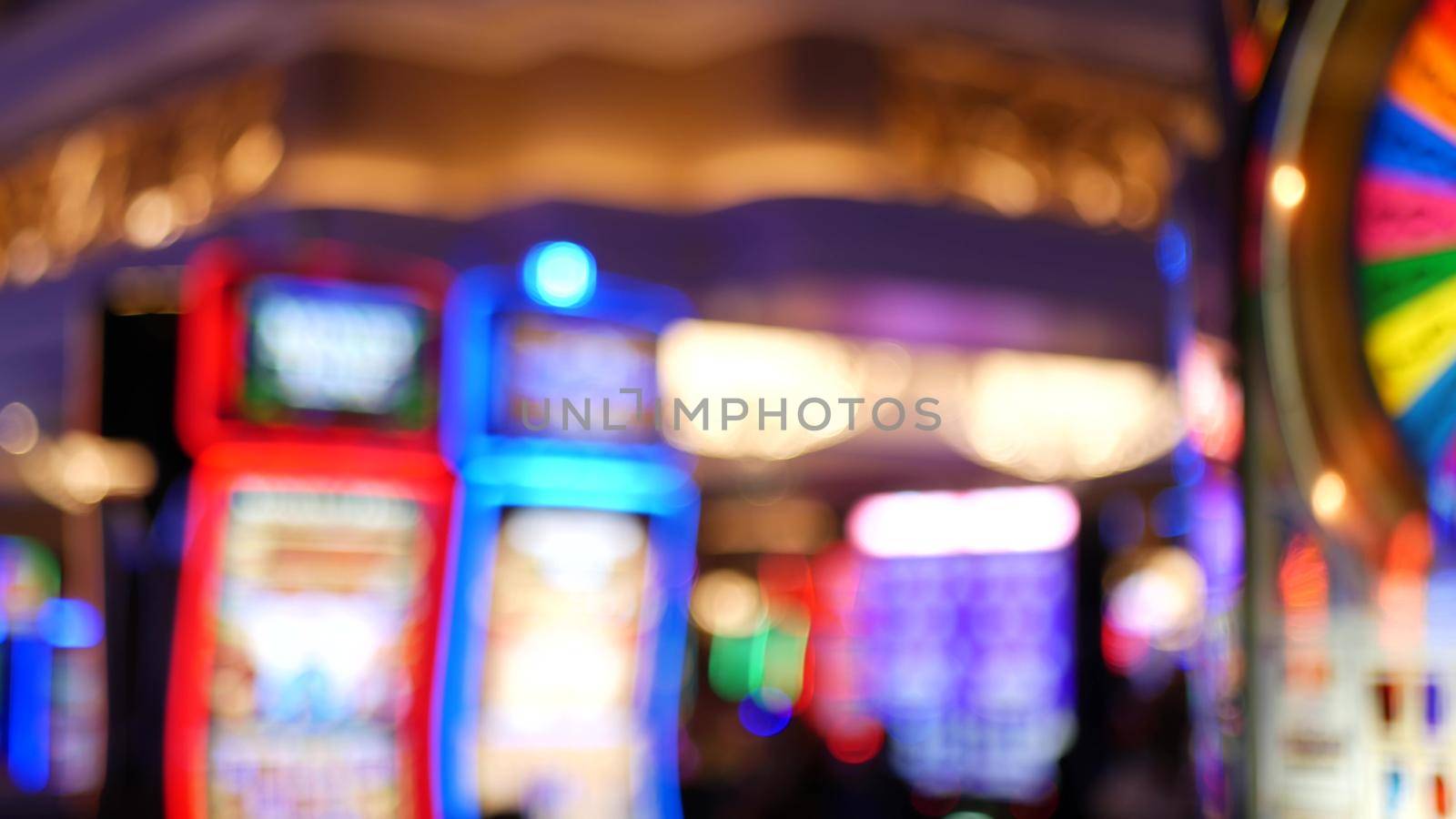 Defocused slot machines glow in casino on fabulous Las Vegas Strip, USA. Blurred gambling jackpot slots in hotel near Fremont street. Illuminated neon fruit machine for risk money playing and betting.