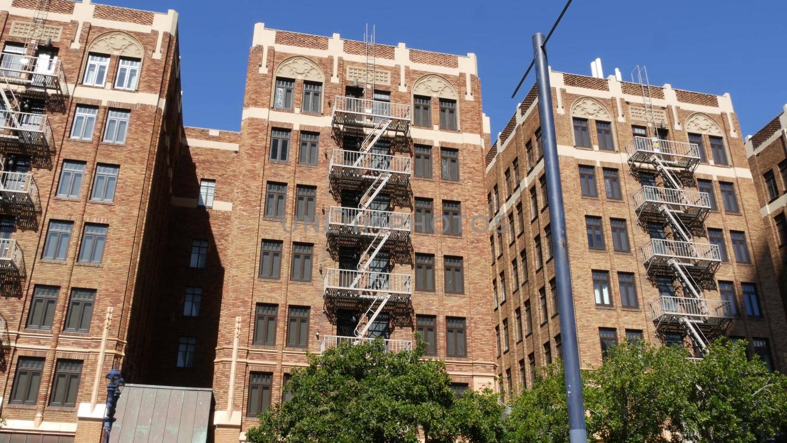 Fire escape ladder outside residential brick building in San Diego city, USA. Typical New York style emergency exit for safe evacuation. Classic retro house exterior as symbol of real estate property.