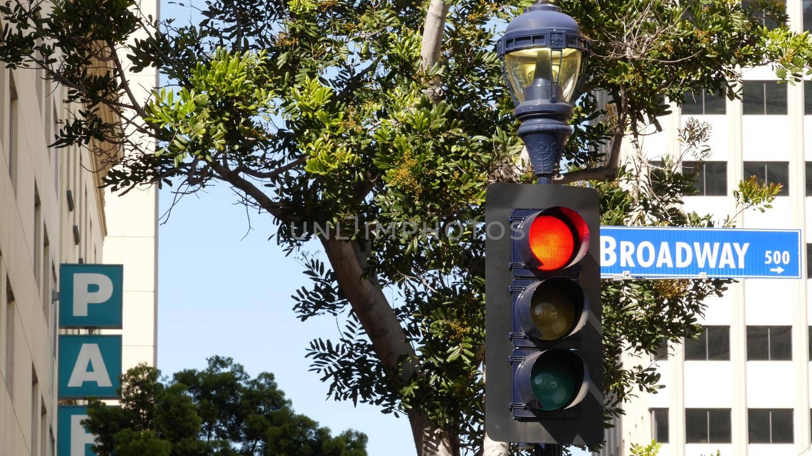 Broadway street name, odonym sign and traffic light on pillar in USA. Road intersection in downtown of city. Crossroad in urban central business district. Nameplate banner with title of main avenue.