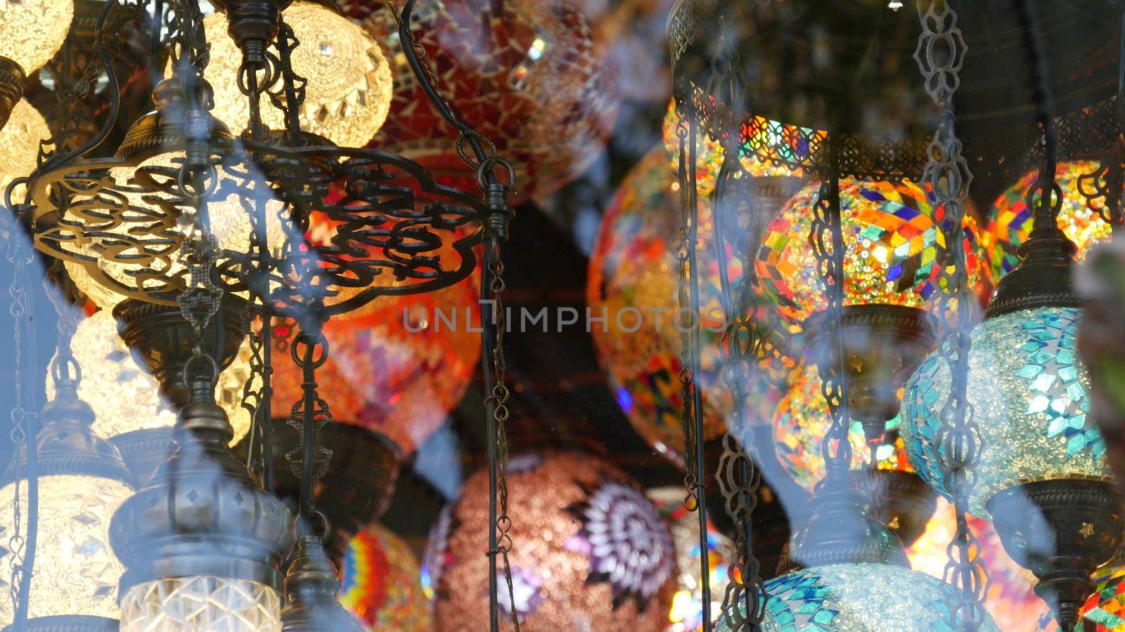Colourful turkish lamps from glass mosaic glowing. Arabic multi colored authentic retro style lights. Many illuminated moroccan craft lanterns. Oriental islamic middle eastern decor. Shiny folk shop.