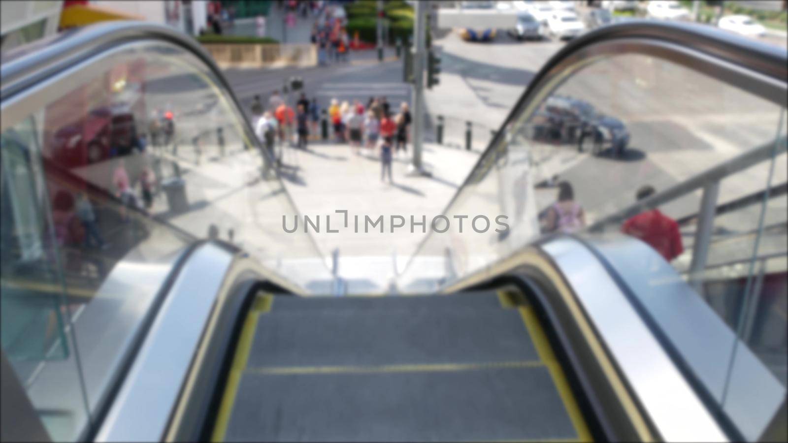 Perspective view thru escalator, defocused unrecognizable group of people on road intersection crosswalk on Strip of Las Vegas, USA. Anonymous blurred pedestrians on walkway in crowded urban downtown.