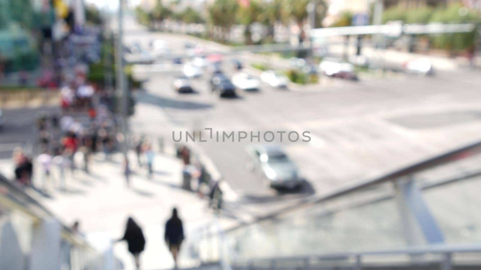 Perspective view thru escalator, defocused unrecognizable group of people on road intersection crosswalk on Strip of Las Vegas, USA. Anonymous blurred pedestrians on walkway in crowded urban downtown by DogoraSun