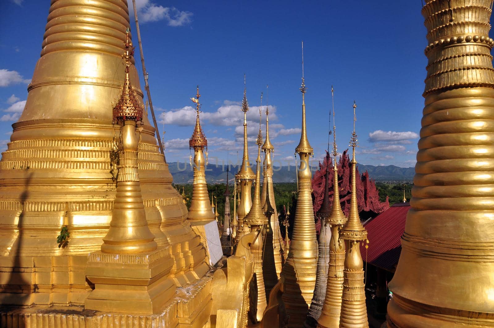 Exterior of exotic temple with stupas and payas, From below shot of golden bright stupas of temple on lake Inle under blue sky, Myanmar. Sacred place.