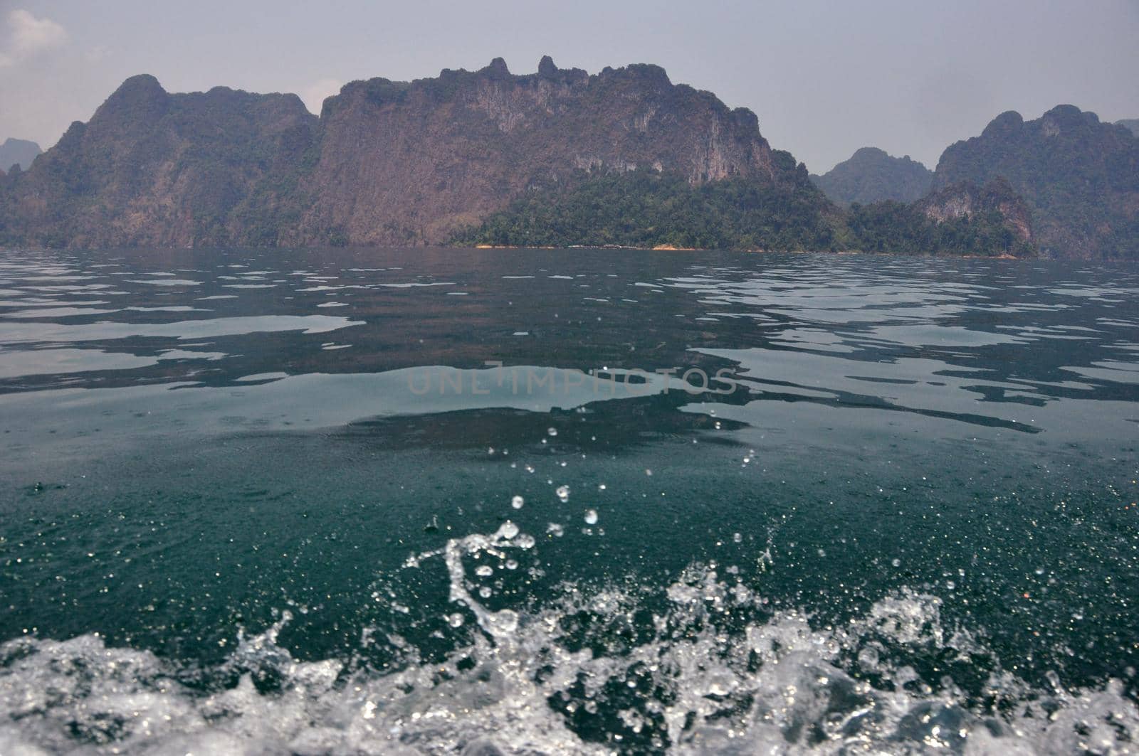 Splashing waves of tropical bay with cliffs, Clear fresh splashes of waves of blue clear water with rocky cliffs on background, Thailand, Khao Sok National park. by DogoraSun